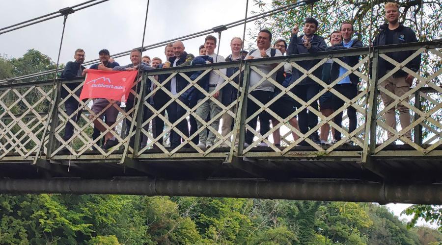 Guys on a bridge with an outdoorlads flag