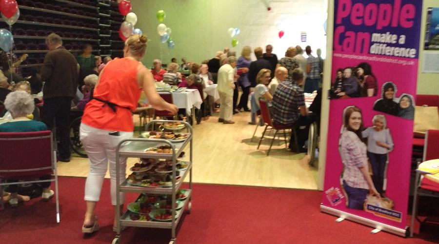 An event at Bingley Little Theatre showing people seated at tables and getting refreshments next to a pop up banner