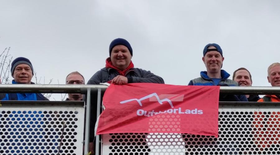 Outdoorlads members with red flag on the bridge into Bingley