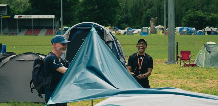 Two men putting up a tent awning
